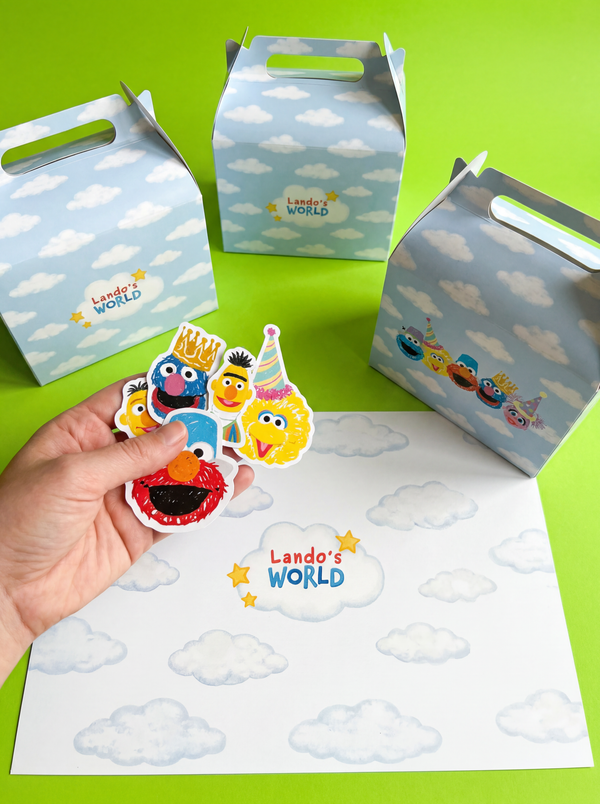 Personalised prints we made of cartoon characters held by a hand with 'Lando's World' branded boxes in the background. Custom cut confetti, party boxes & place mats!